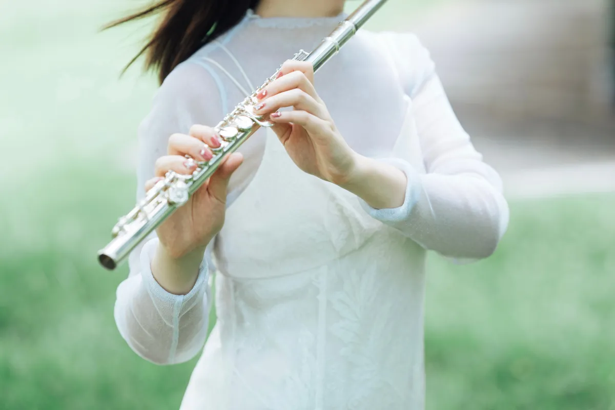 永田梨紗が髪を靡かせながら森でフルートを吹いている写真