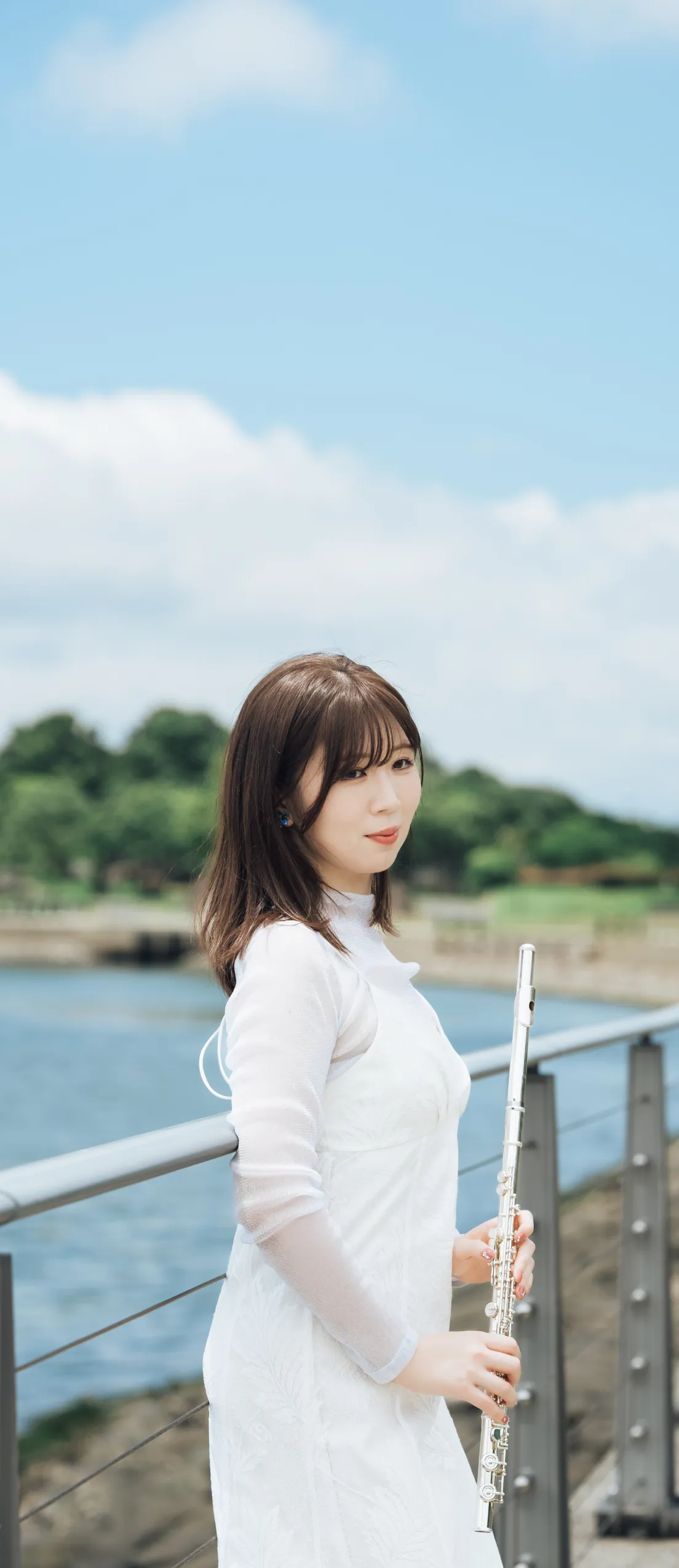 永田梨紗が海の見える場所でフルートを持っている写真